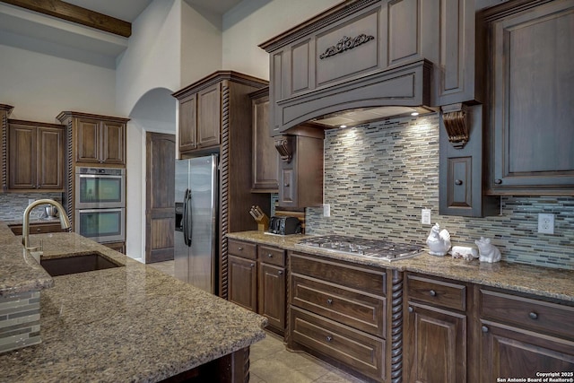26358 Tawny Way, Boerne, TX 78015 - kitchen featuring stainless steel appliances, a sink, decorative backsplash, stone countertops, and dark brown cabinetry