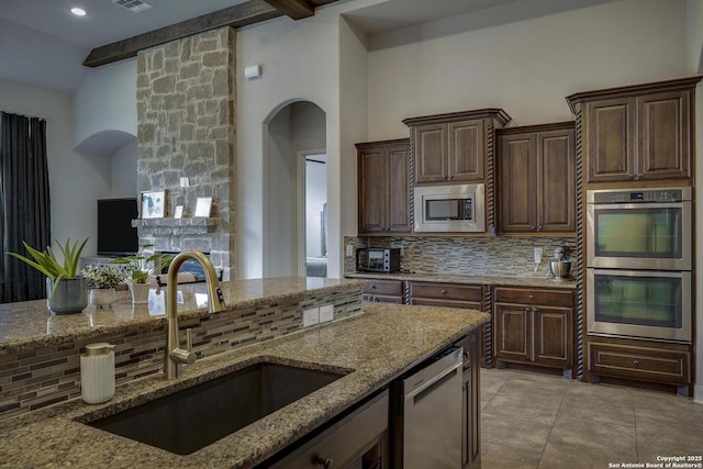 26358 Tawny Way, Boerne, TX 78015 - kitchen featuring stainless steel appliances, a sink, tasteful backsplash, arched walkways, and light stone counters