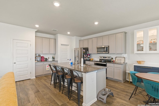 10815 Fox Trot, Converse, TX 78109 - kitchen featuring stainless steel appliances, dark wood-style flooring, tasteful backsplash, a kitchen bar, and a center island with sink