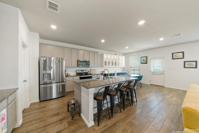 10815 Fox Trot, Converse, TX 78109 - kitchen with appliances with stainless steel finishes, a breakfast bar area, wood finished floors, gray cabinetry, and a kitchen island with sink
