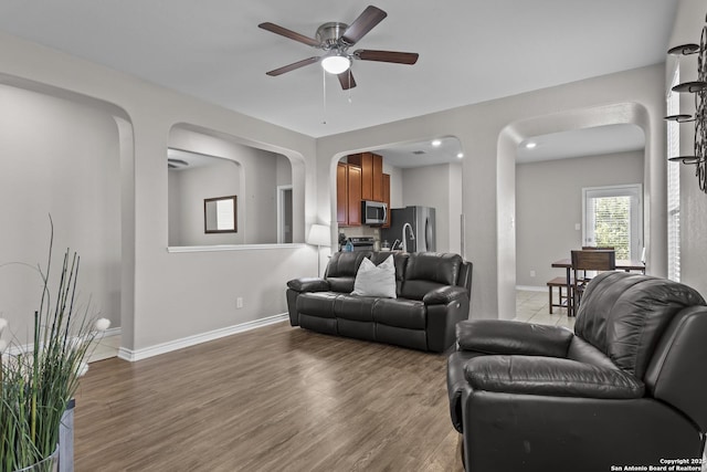 8415 Fortuna Vly, San Antonio, TX 78252 - living area featuring arched walkways, ceiling fan, baseboards, and light wood-style flooring