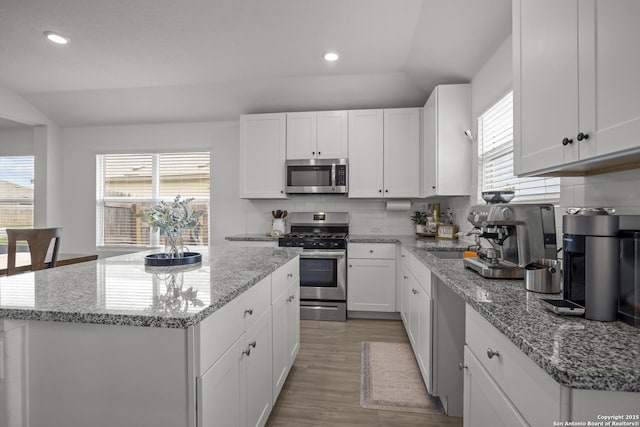 31665 Acacia Vis, Bulverde, TX 78163 - kitchen featuring stainless steel appliances, lofted ceiling, tasteful backsplash, white cabinetry, and a center island