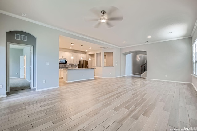 13908 Lazada, San Antonio, TX 78245 - unfurnished living room featuring a ceiling fan, baseboards, arched walkways, light wood-style flooring, and crown molding
