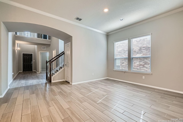 13908 Lazada, San Antonio, TX 78245 - spare room featuring arched walkways, light wood-style flooring, baseboards, ornamental molding, and stairs