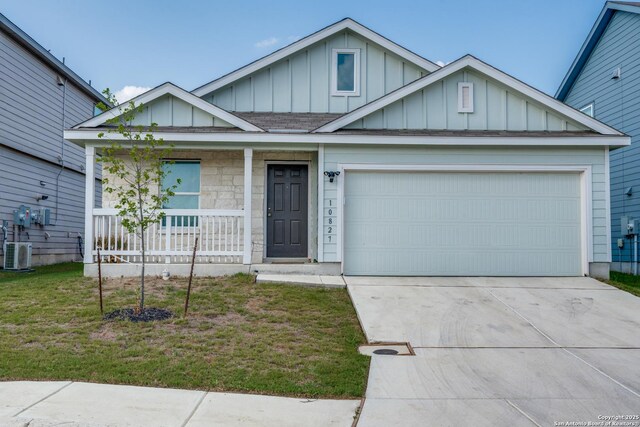 10827 Hernando Ct, Converse, TX 78109 - view of front of home with board and batten siding, covered porch, concrete driveway, a garage, and central AC unit