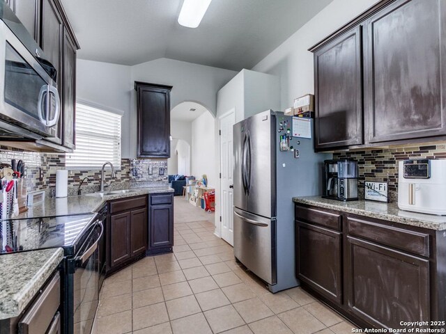 6211 Post Mi, San Antonio, TX 78244 - kitchen featuring stainless steel appliances, a sink, arched walkways, dark brown cabinets, and light tile patterned floors