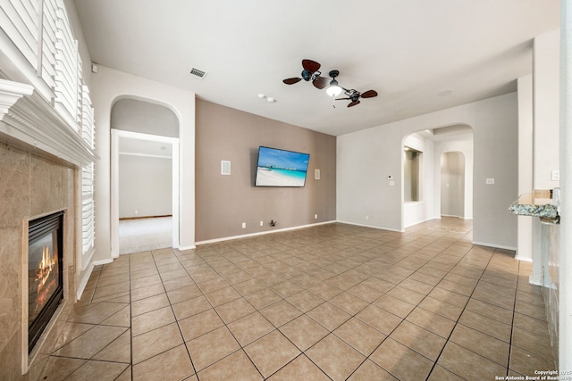 102 Blue Thorn, San Antonio, TX 78256 - unfurnished living room with ceiling fan, a fireplace, light tile patterned floors, arched walkways, and baseboards