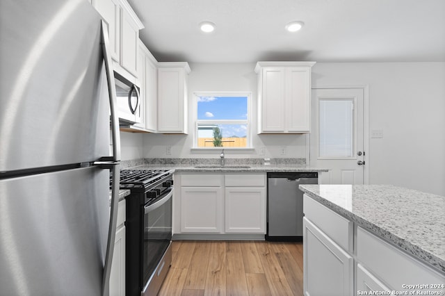 12055 Luckey Villa, San Antonio, TX 78252 - kitchen with appliances with stainless steel finishes, a sink, white cabinets, light wood-style flooring, and recessed lighting