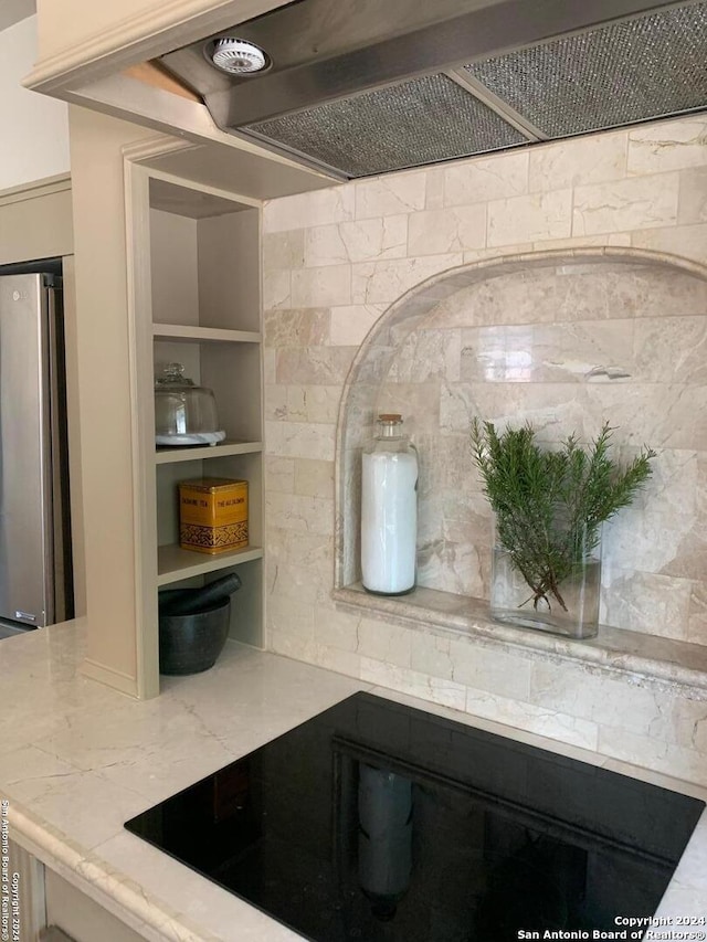 12111 Woodsrim, Live Oak, TX 78233 - kitchen view of freestanding refrigerator, black electric stovetop, wall chimney range hood, and light stone countertops