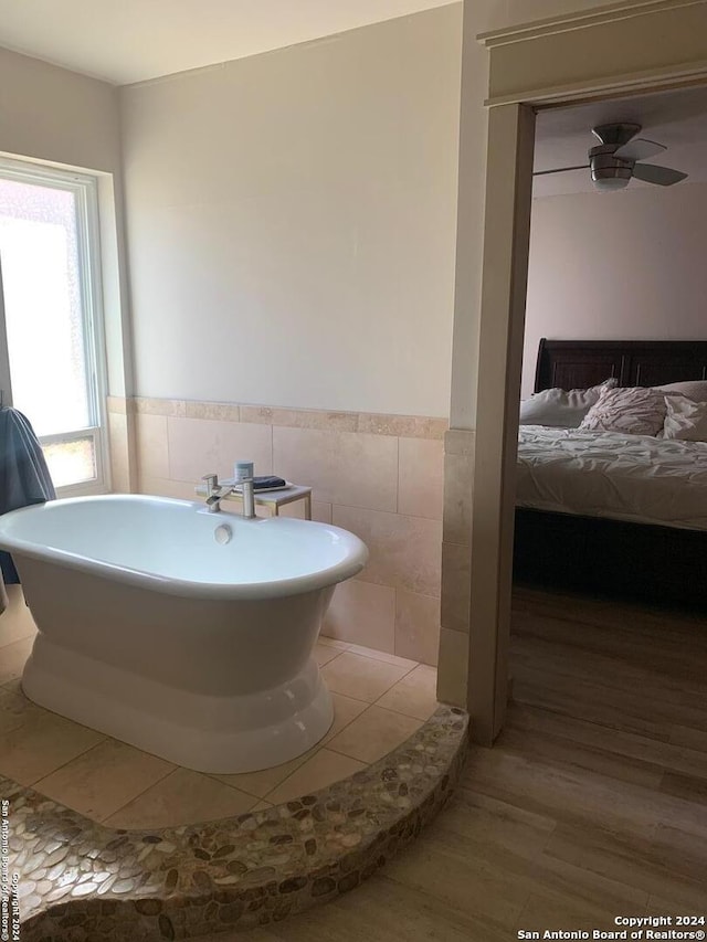 12111 Woodsrim, Live Oak, TX 78233 - bathroom featuring tile walls, a soaking tub, wood finished floors, and a wainscoted wall