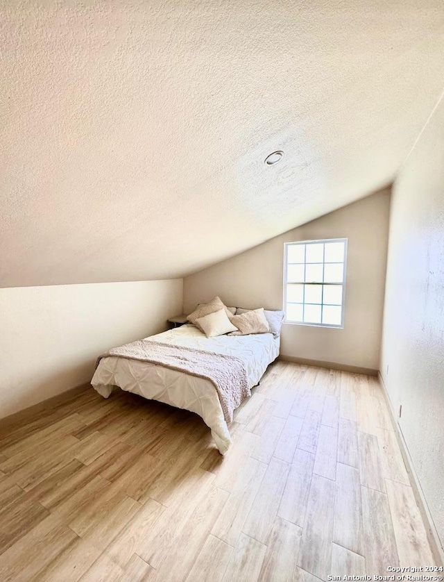 12111 Woodsrim, Live Oak, TX 78233 - bedroom featuring vaulted ceiling, light wood-style flooring, and a textured ceiling