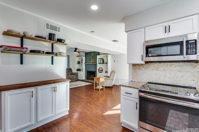 3618 Minthill, San Antonio, TX 78230 - kitchen featuring appliances with stainless steel finishes, a fireplace, dark wood-type flooring, backsplash, and white cabinets