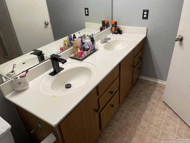 9858 Menard Cir, San Antonio, TX 78245 - bathroom featuring a textured wall, double vanity, and tile patterned flooring