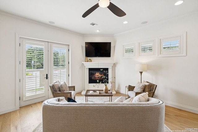 172 Katherine Ct Unit 1, San Antonio, TX 78209 - living area featuring crown molding, a ceiling fan, light wood-type flooring, a glass covered fireplace, and baseboards