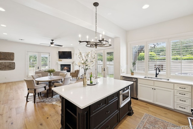 172 Katherine Ct Unit 1, San Antonio, TX 78209 - kitchen featuring stainless steel dishwasher, a sink, light countertops, a warm lit fireplace, and recessed lighting
