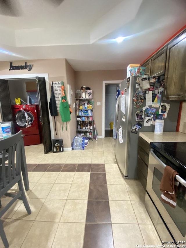 1202 Pine, Orange, TX 77630 - kitchen featuring washer / dryer, electric stove, light countertops, light tile patterned flooring, and dark brown cabinets