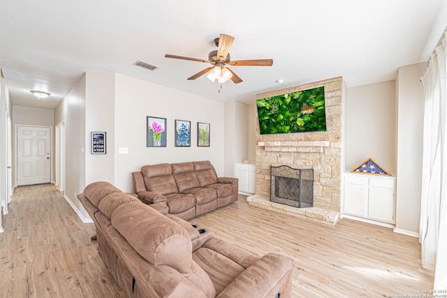 132 Las Palomas Ln, Vernia, TX 78121 - living area featuring light wood-type flooring, a ceiling fan, a stone fireplace, and baseboards
