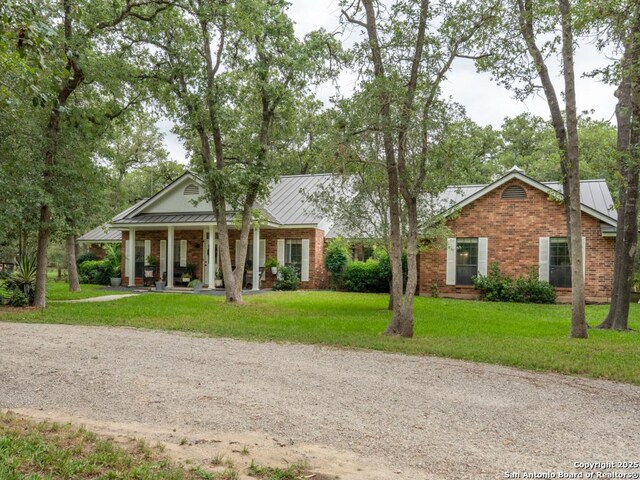 120 Spanish Oak Trl, Floresville, TX 78114 - view of front of home with covered porch, brick siding, a front yard, and a standing seam roof