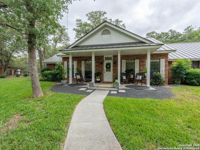 120 Spanish Oak Trl, Floresville, TX 78114 - view of front facade with a standing seam roof, covered porch, a front lawn, metal roof, and brick siding