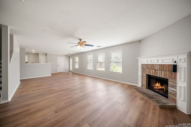 11907 Creek Peak, San Antonio, TX 78253 - unfurnished living room with a brick fireplace, wood finished floors, ceiling fan, baseboards, and stairs