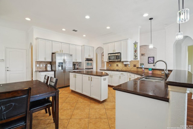 7027 Laura Hts, Schertz, TX 78154 - kitchen with stainless steel appliances, arched walkways, a sink, dark countertops, and a peninsula