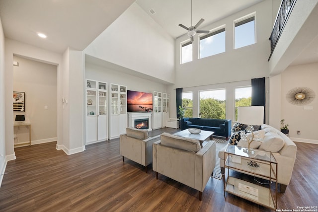 418 Sundance Way, San Antonio, TX 78253 - living area with ceiling fan, a warm lit fireplace, dark wood finished floors, baseboards, and a towering ceiling
