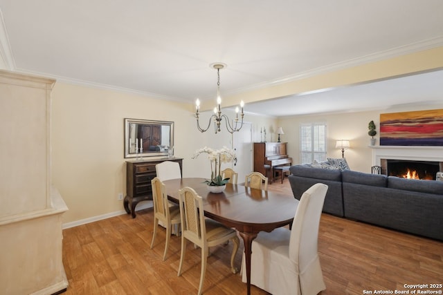 107-A Ruelle Unit 107-A, San Antonio, TX 78209 - dining space with ornamental molding, a chandelier, light wood finished floors, a warm lit fireplace, and baseboards