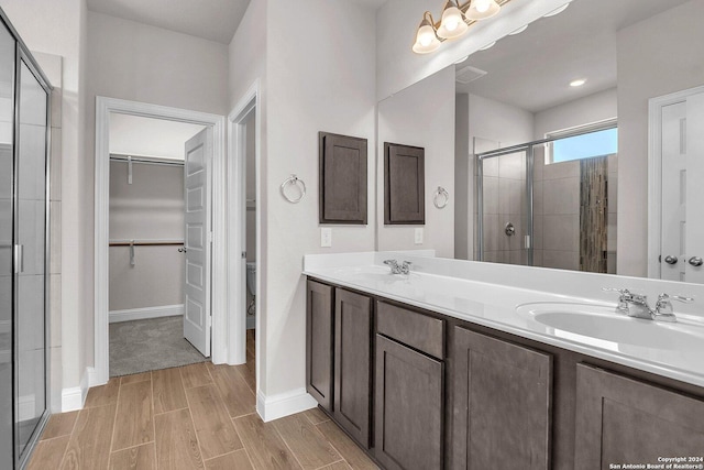 6538 Scooby Acres, San Antonio, TX 78108 - full bathroom with a shower stall, a walk in closet, double vanity, wood finish floors, and baseboards