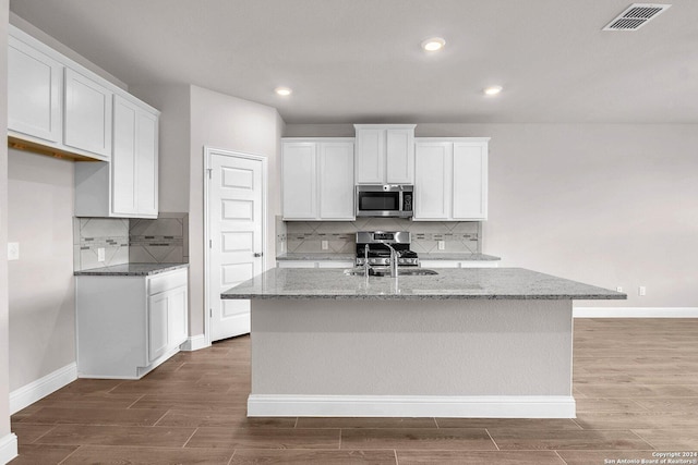 6538 Scooby Acres, San Antonio, TX 78108 - kitchen featuring stainless steel appliances, wood finished floors, baseboards, an island with sink, and light stone counters