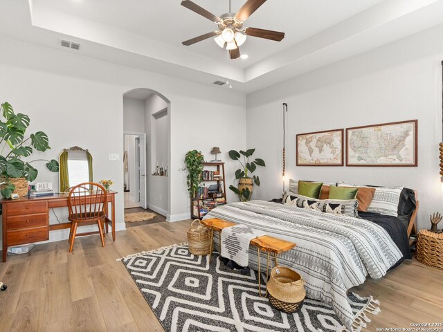 4508 River Rock, Marion, TX 78124 - bedroom featuring arched walkways, a raised ceiling, light wood-type flooring, recessed lighting, and baseboards