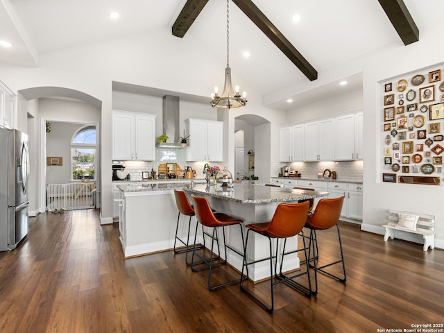 4508 River Rock, Marion, TX 78124 - kitchen with stainless steel fridge, wall chimney exhaust hood, arched walkways, beamed ceiling, and tasteful backsplash