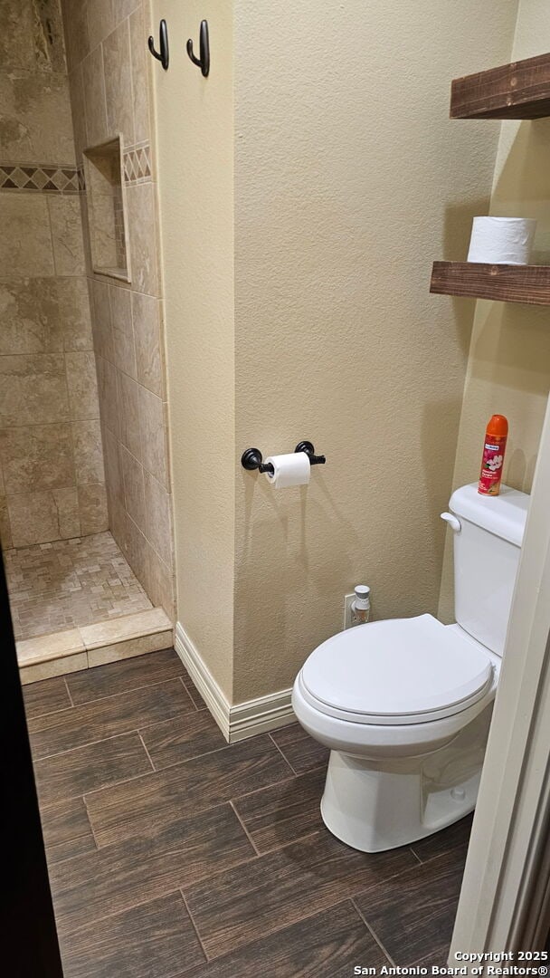 218 E Antonio, Uvalde, TX 78801 - full bathroom with toilet, a tile shower, wood finished floors, and baseboards