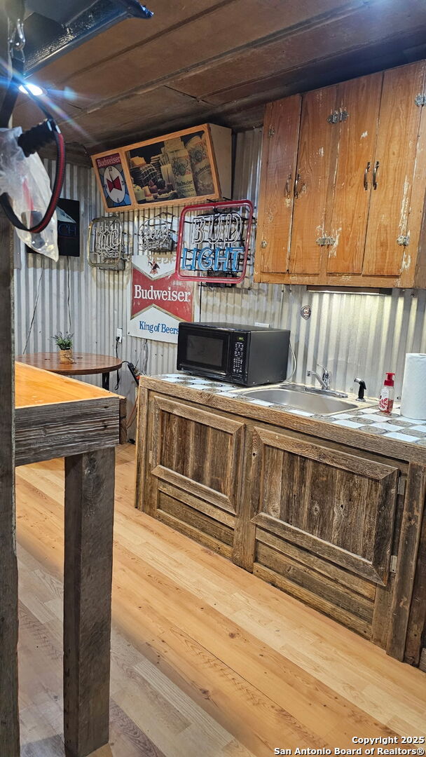 218 E Antonio, Uvalde, TX 78801 - bar area with black microwave, wood finished floors, and a sink