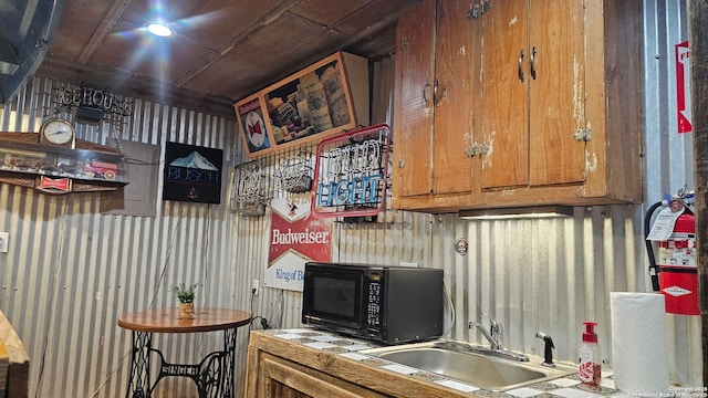 218 E Antonio, Uvalde, TX 78801 - kitchen with black microwave, a sink, wallpapered walls, and brown cabinets
