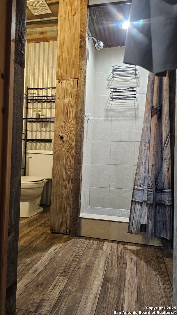 218 E Antonio, Uvalde, TX 78801 - bathroom featuring toilet, wood finished floors, and tiled shower