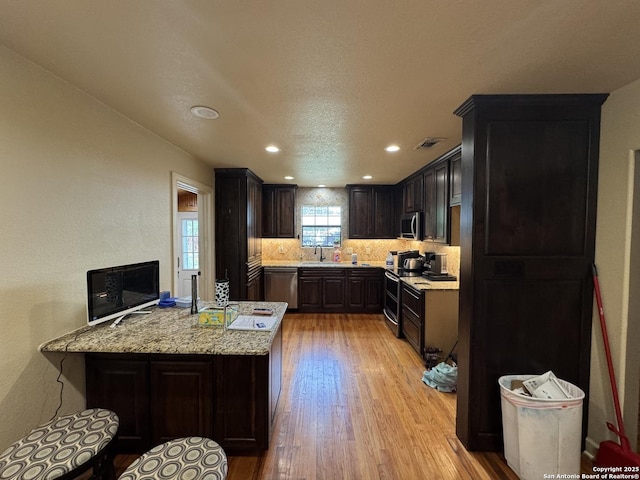 218 E Antonio, Uvalde, TX 78801 - kitchen with stainless steel appliances, light wood finished floors, a peninsula, backsplash, and recessed lighting