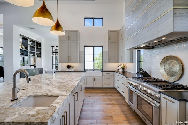 121 Greystone Pt, Boerne, TX 78006 - kitchen with range with two ovens, a sink, premium range hood, light wood-type flooring, and a towering ceiling