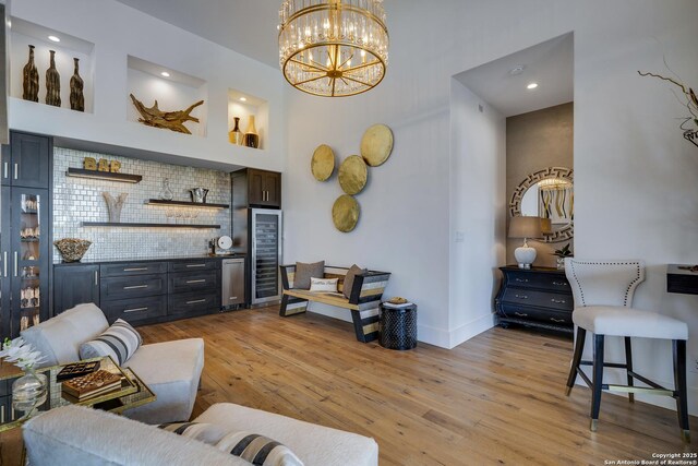 121 Greystone Pt, Boerne, TX 78006 - living area with wine cooler, a bar, light wood-style floors, a chandelier, and baseboards