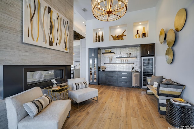 121 Greystone Pt, Boerne, TX 78006 - living area featuring beverage cooler, light wood-style floors, a tiled fireplace, bar, and a chandelier