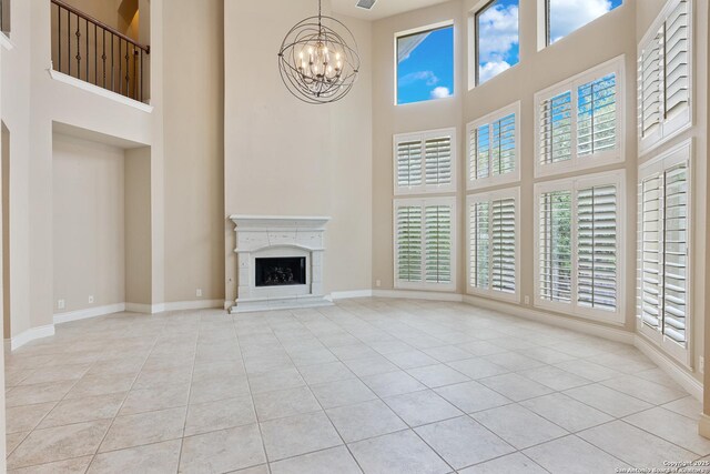 27711 Woodway Bnd, Boerne, TX 78006 - unfurnished living room with a towering ceiling, a chandelier, healthy amount of natural light, tile patterned floors, and a high end fireplace