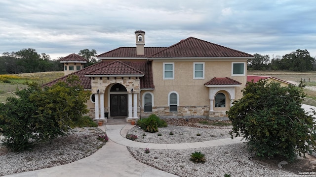 113 Abrego Mt, Floresville, TX 78114 - mediterranean / spanish home with a chimney, stone siding, a tiled roof, and stucco siding