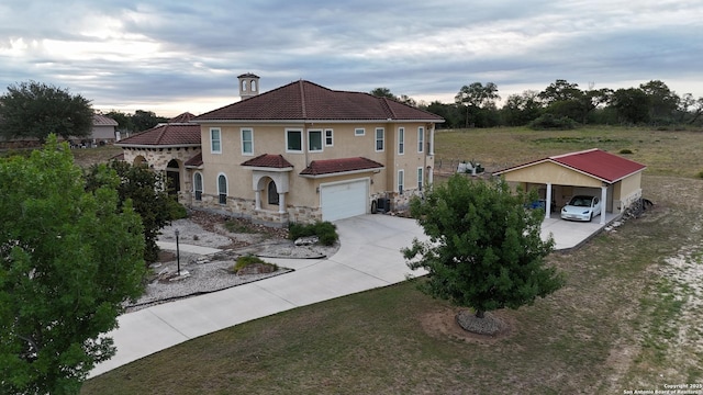 113 Abrego Mt, Floresville, TX 78114 - mediterranean / spanish-style home featuring driveway, an attached garage, stone siding, stucco siding, and a detached carport