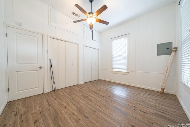 2310 W Houston St, San Antonio, TX 78207 - unfurnished bedroom with multiple closets, wood finished floors, electric panel, and multiple windows