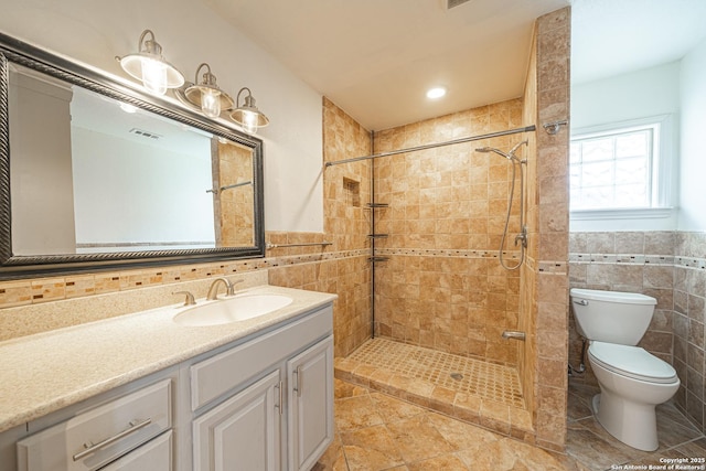 2310 W Houston St, San Antonio, TX 78207 - bathroom featuring tile walls, toilet, a shower stall, vanity, and a wainscoted wall
