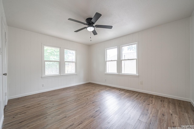 2310 W Houston St, San Antonio, TX 78207 - empty room with wood finished floors, a ceiling fan, a textured ceiling, and baseboards