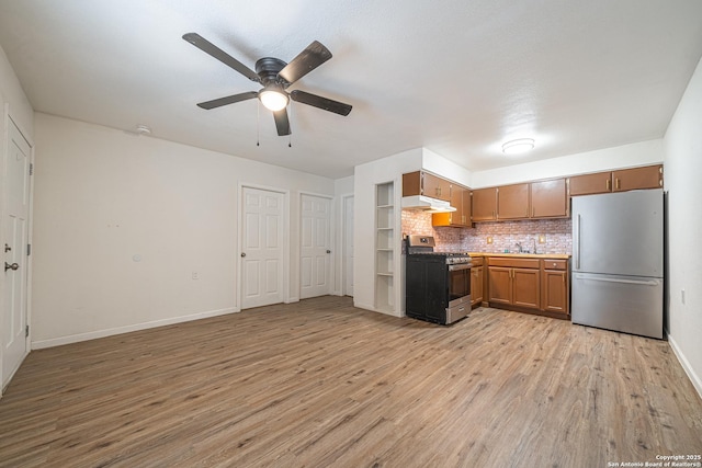 2310 W Houston St, San Antonio, TX 78207 - kitchen featuring appliances with stainless steel finishes, under cabinet range hood, ceiling fan, light wood-style flooring, and tasteful backsplash