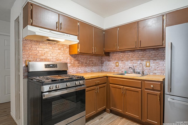 2310 W Houston St, San Antonio, TX 78207 - kitchen with stainless steel appliances, under cabinet range hood, a sink, light wood finished floors, and backsplash