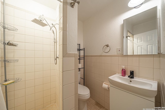 2310 W Houston St, San Antonio, TX 78207 - full bathroom with tiled shower, vanity, tile walls, toilet, and a wainscoted wall