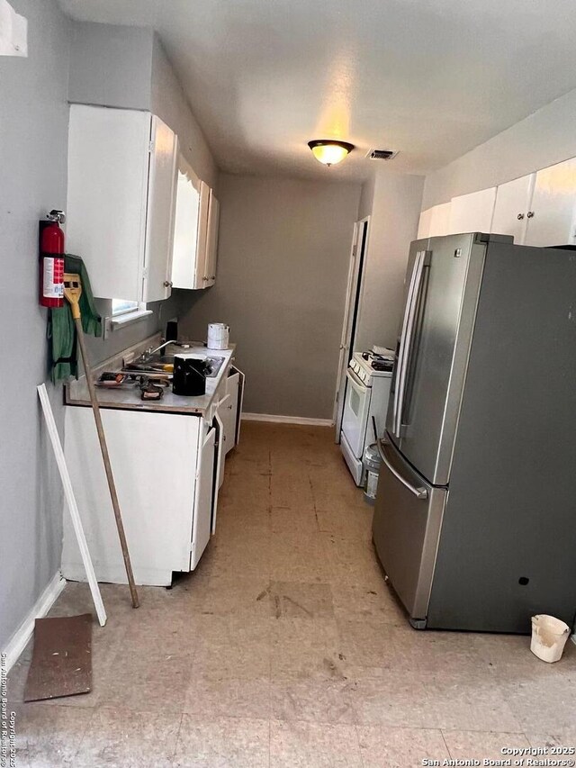 115 Westhaven Pl, San Antonio, TX 78227 - kitchen featuring freestanding refrigerator, white range with gas stovetop, baseboards, white cabinets, and light flooring