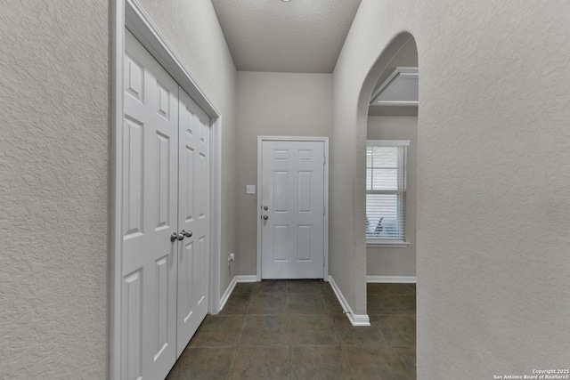 5327 Gemsbuck Chase, San Antonio, TX 78251 - entrance foyer with a textured wall, dark tile patterned flooring, arched walkways, baseboards, and a textured ceiling
